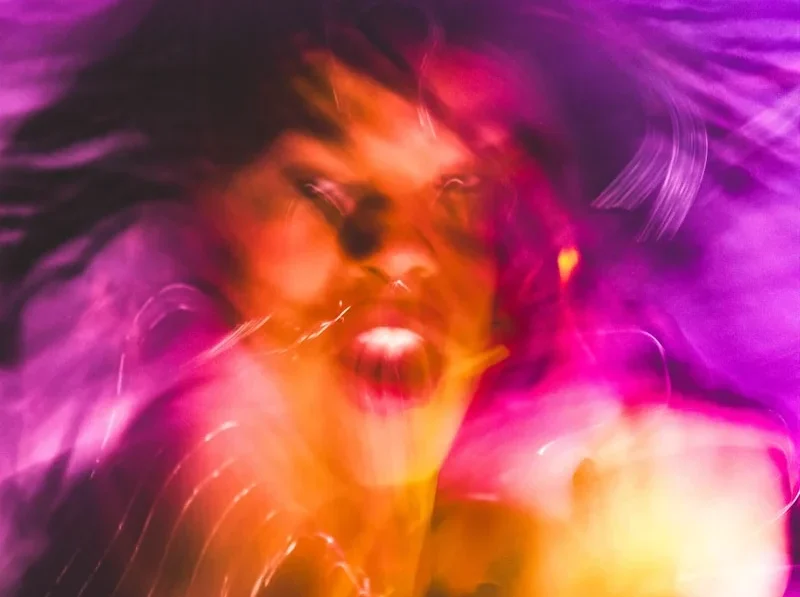 A blurry photo of a woman with her hair blowing in the wind