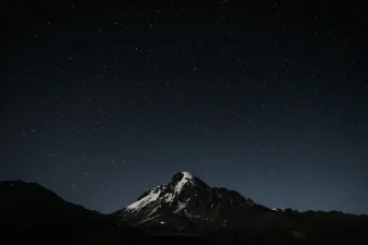 The night sky with stars above a mountain