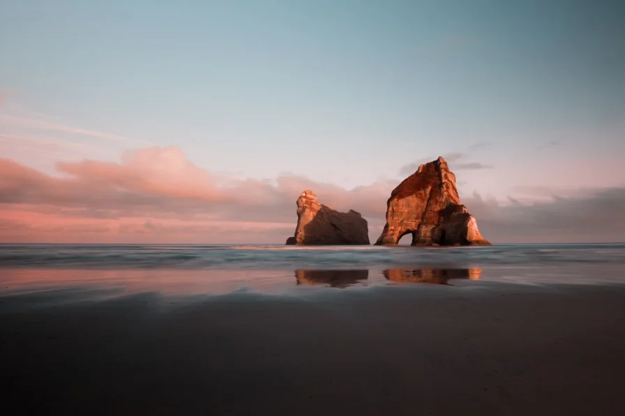 A large rock sitting on top of a beach next to the ocean